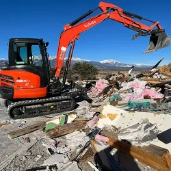 Backhoe excavator performing debris cleanup on a property